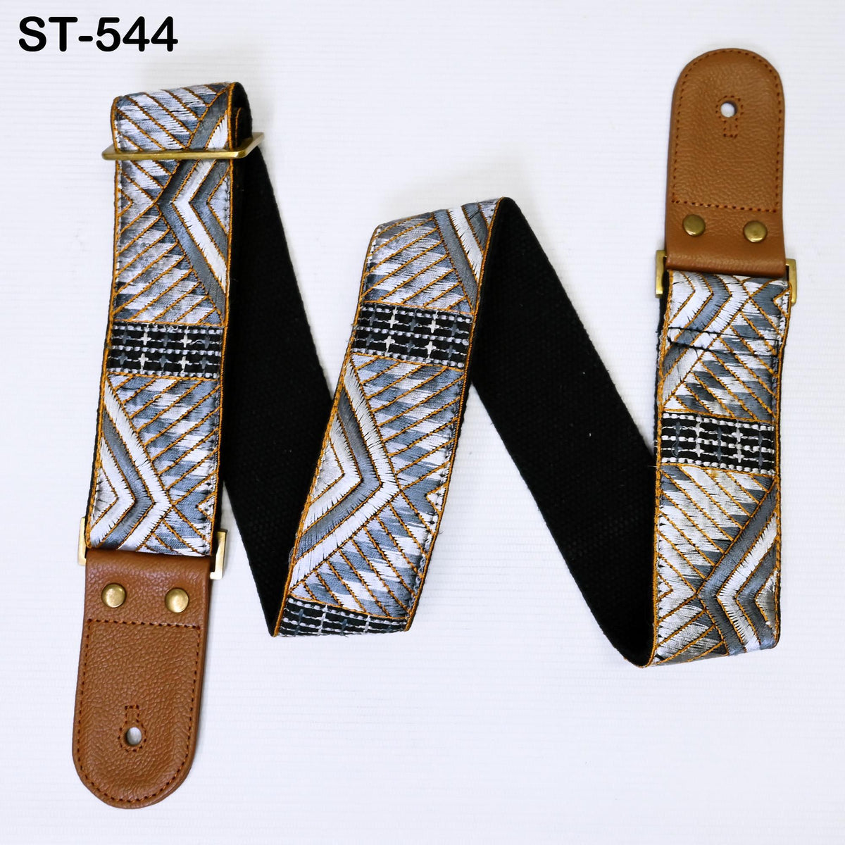 A guitar strap with a geometric pattern in shades of gray and white, featuring a brown leather buckle.