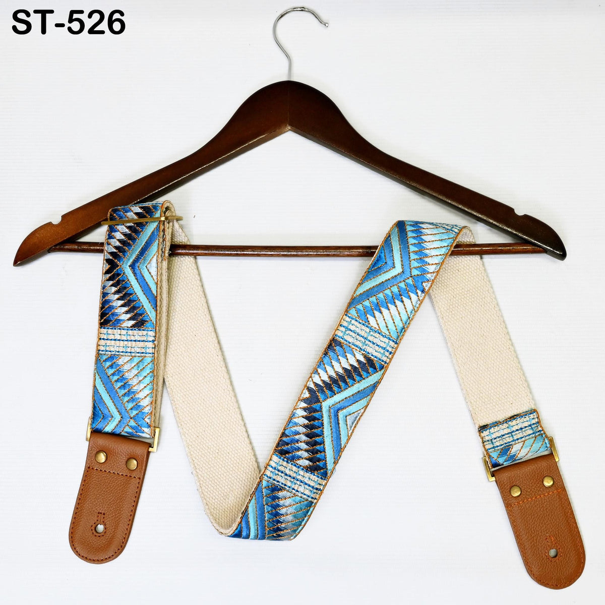 A wooden hanger with a patterned fabric strap is displayed against a white background.