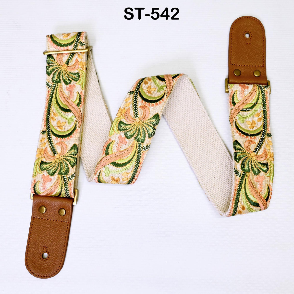 A colorful guitar strap with a floral pattern, featuring a combination of green, orange, and pink colors. The strap appears to be made of a soft, woven material and has a leather-like texture.