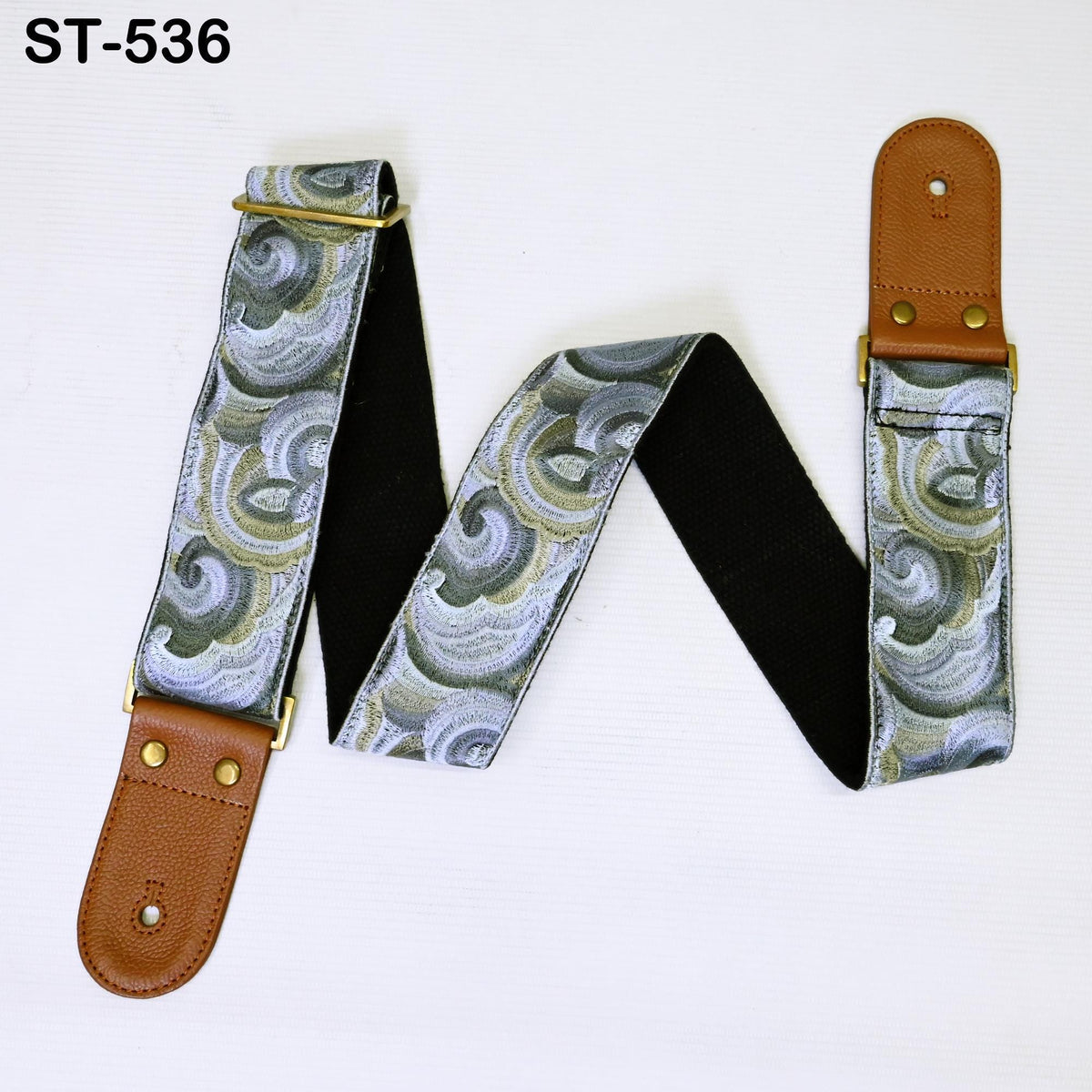 A guitar strap with a floral pattern and a brown leather buckle.