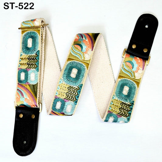 A colorful guitar strap with a floral pattern and a black leather buckle.