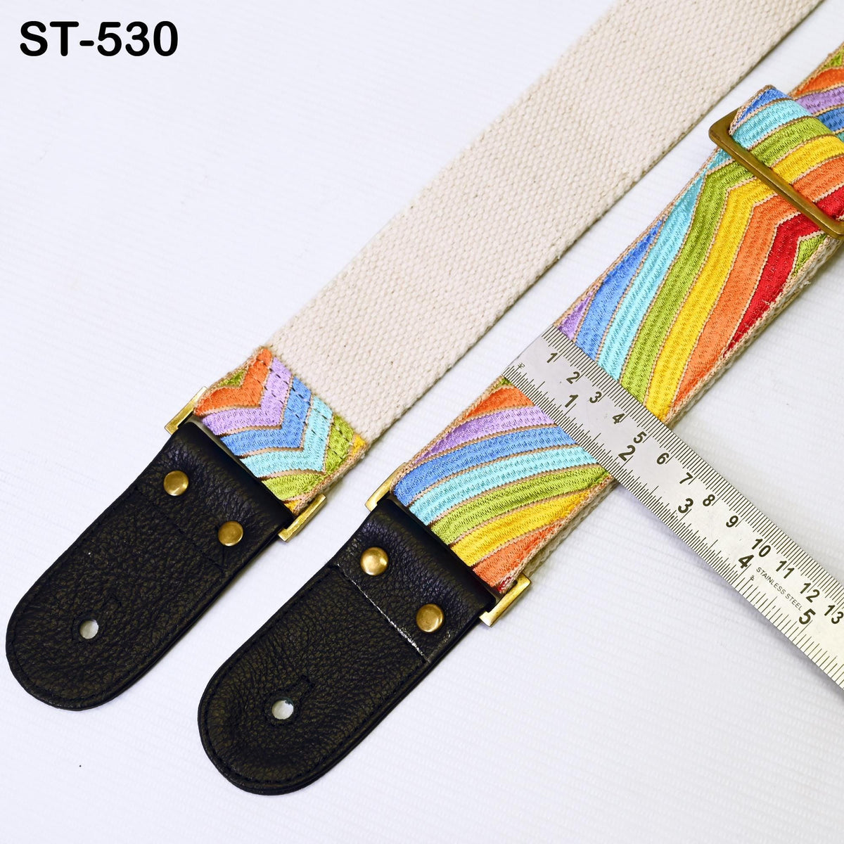a colorful guitar strap with a ruler placed next to it, indicating the strap's length.