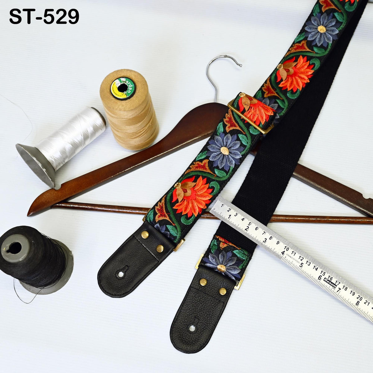 a variety of craft supplies, including a spool of thread, a wooden hanger, a ruler, and a colorful fabric with a floral pattern.