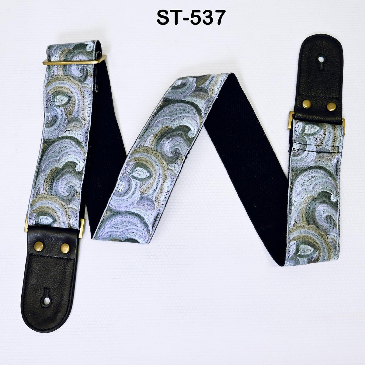 A guitar strap with a patterned design, featuring a black leather-like material and a black leather buckle.