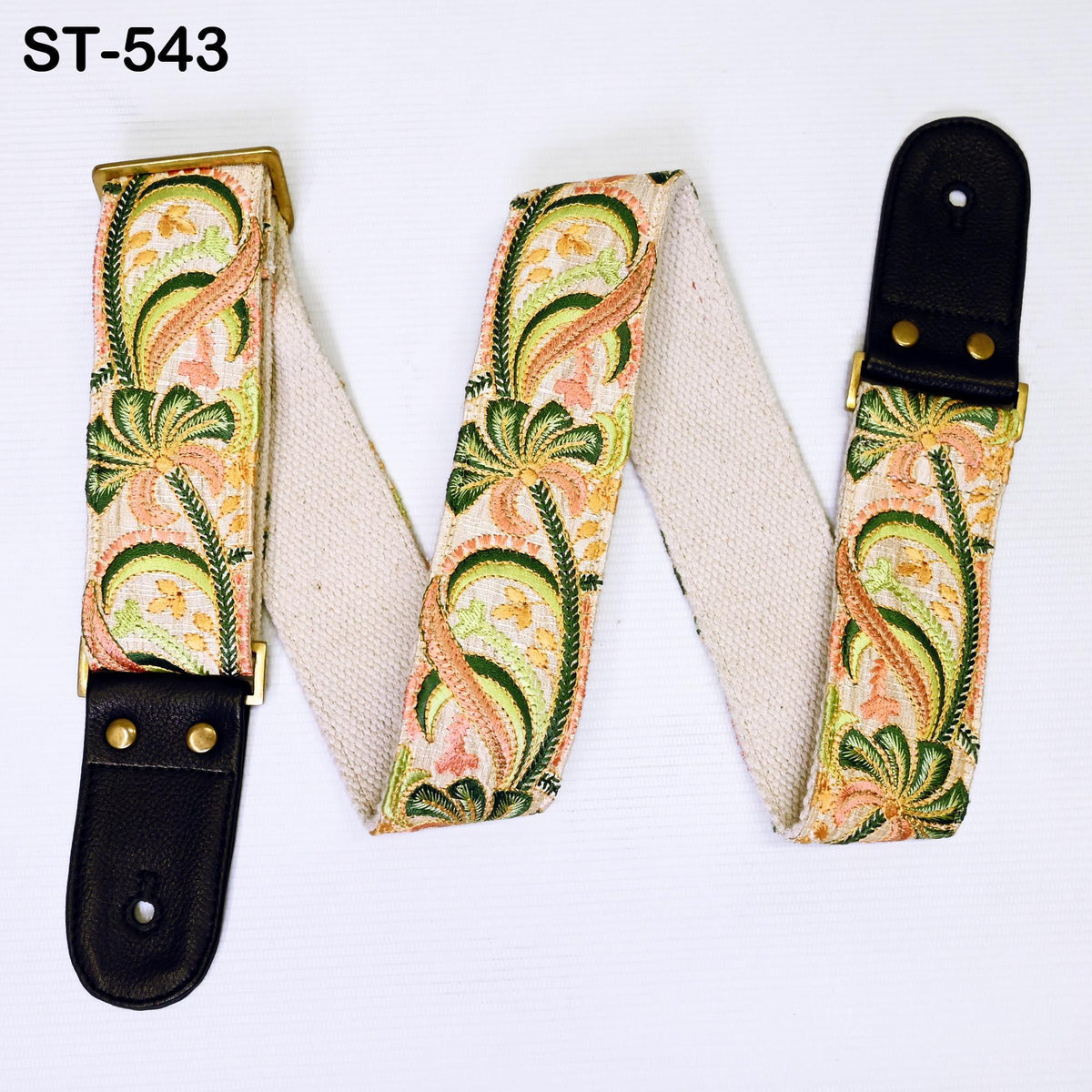 A colorful guitar strap with a floral pattern, featuring a combination of green, orange, and pink colors. The strap appears to be made of a soft, woven material and is attached to a black leather buckle.