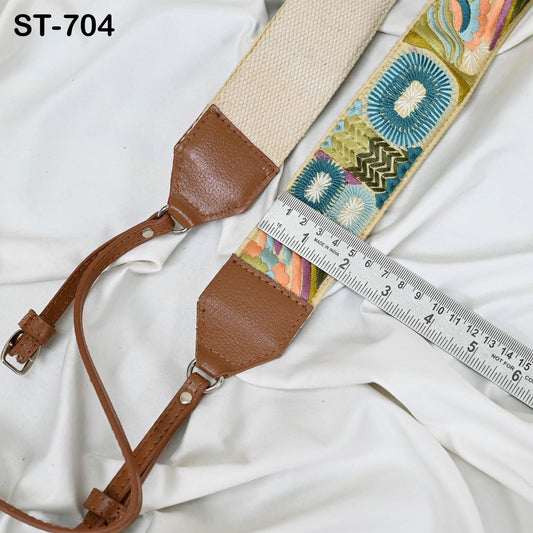 A beige strap with a colorful floral pattern and a brown leather strap are placed on a white fabric surface, with a ruler for size comparison.