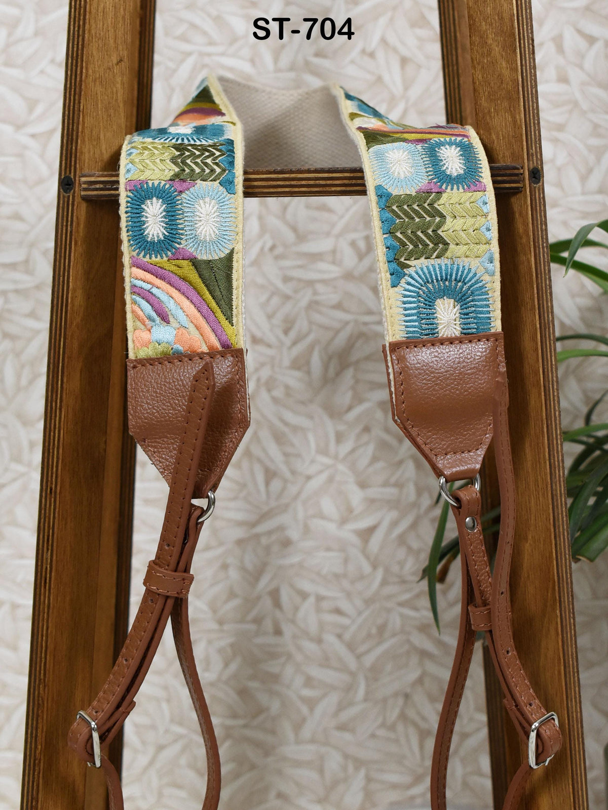 A pair of colorful, patterned camera straps hanging on a wooden stand.