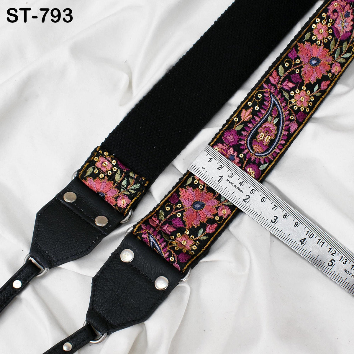 A black strap with a floral pattern and a ruler placed on top of it, indicating the strap's length.