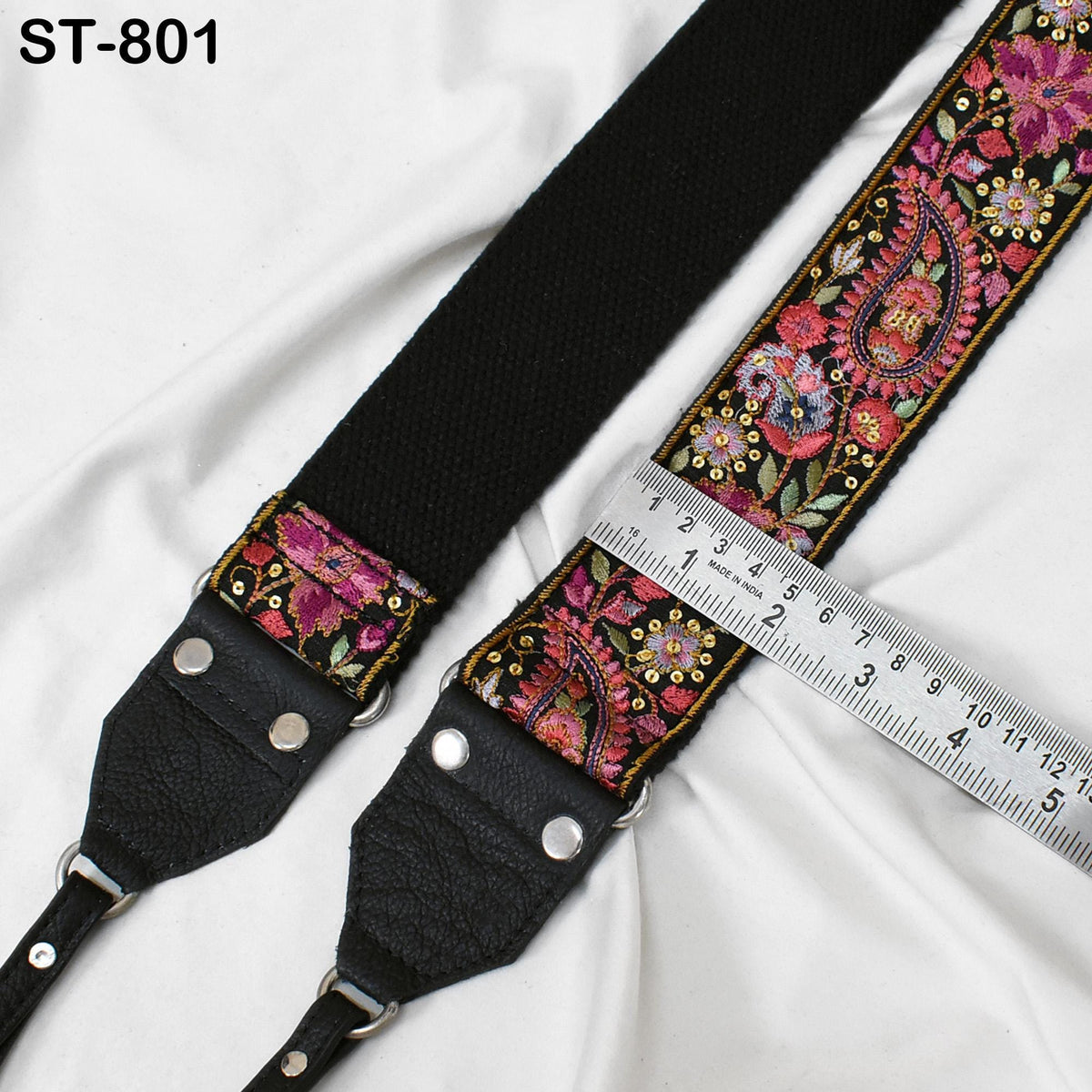 A black and pink patterned strap with a ruler placed on top of it, indicating the strap's length.