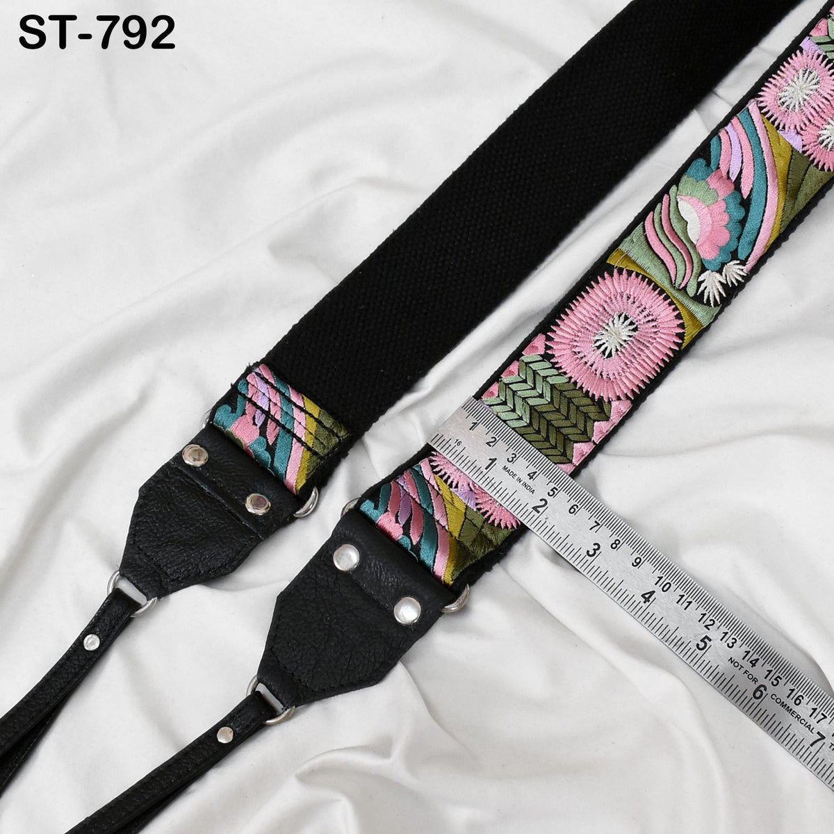 A colorful, patterned strap with a black buckle and a ruler placed next to it, indicating the strap's size.