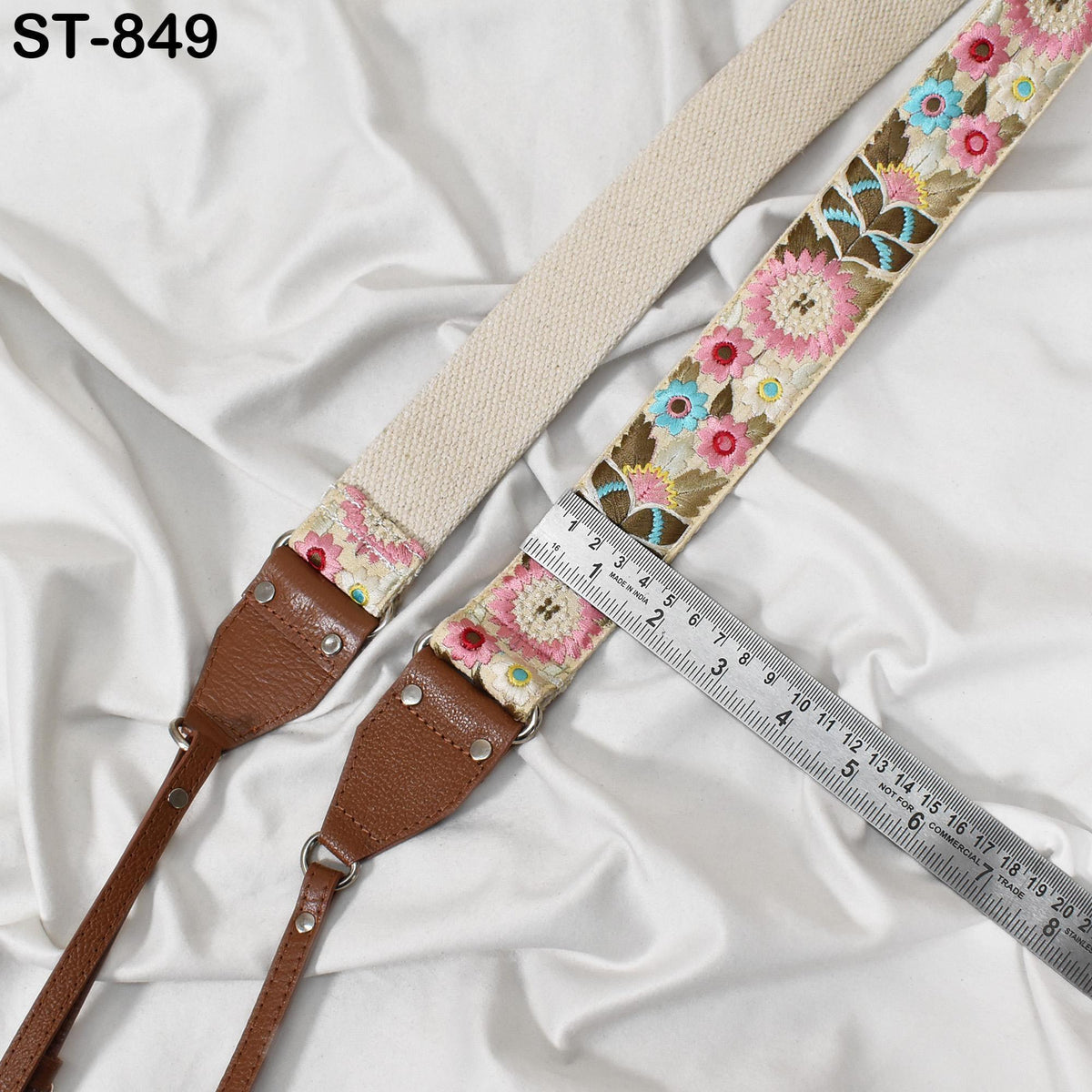 a beige strap with a floral pattern, placed on a white fabric surface. A metal ruler is positioned next to the strap, indicating the strap's length.