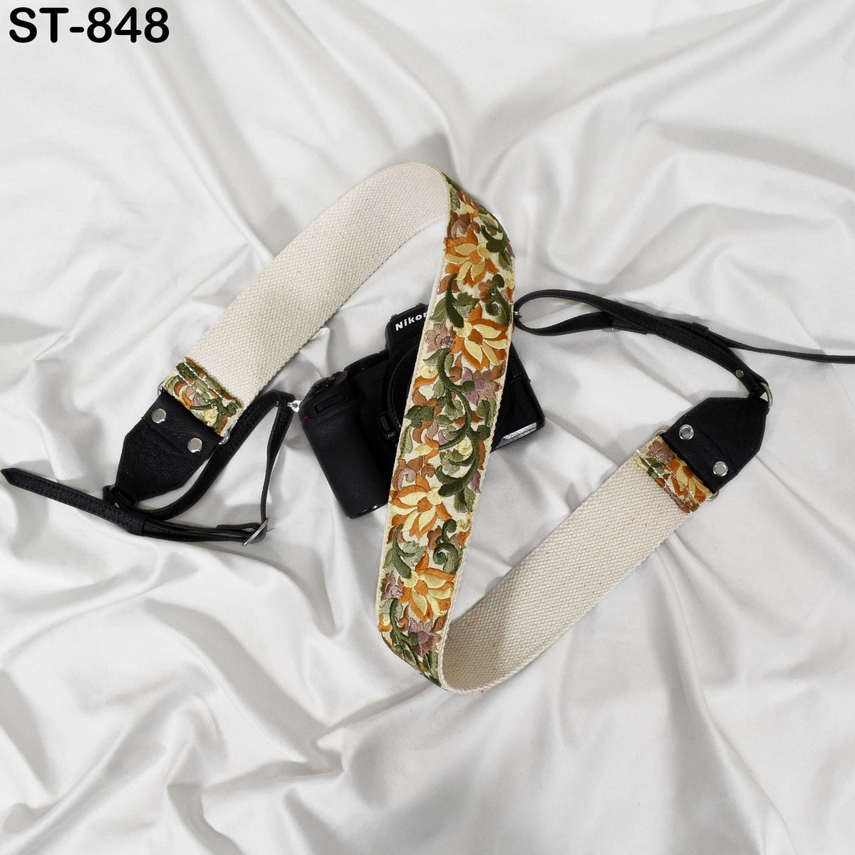 A camera strap with a floral pattern is placed on a white surface.