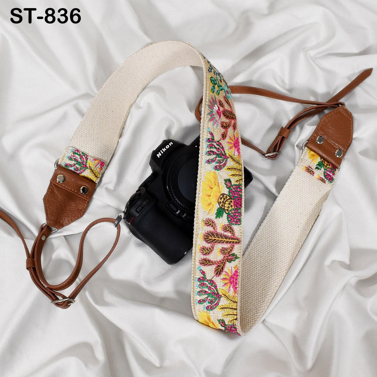A black camera with a colorful strap is placed on a white surface.