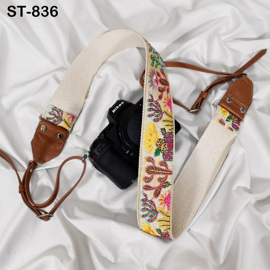 A black camera with a colorful strap is placed on a white surface.