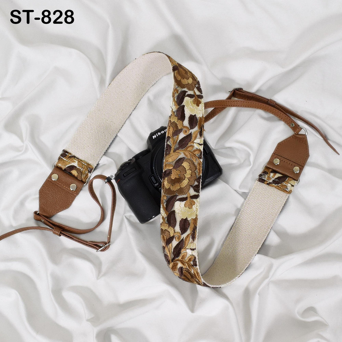 A floral patterned camera strap is draped over a black camera, with a white background.
