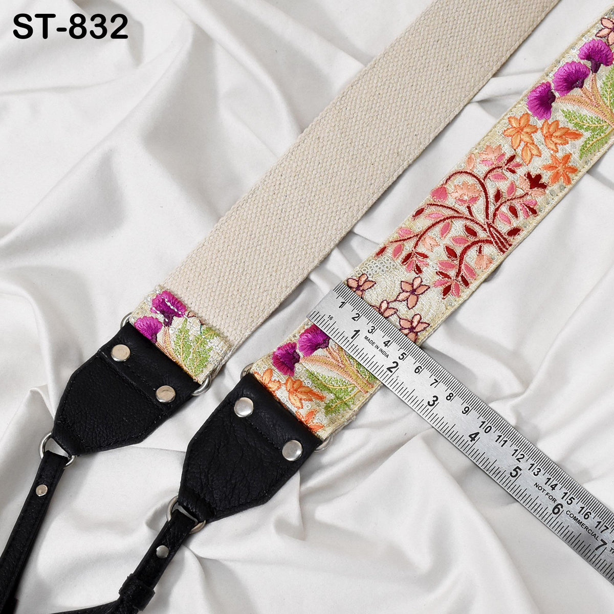 a camera strap with a floral pattern and a ruler placed next to it, indicating the strap's length.