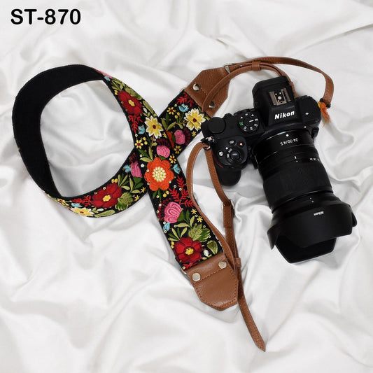 A floral patterned camera strap and a Nikon camera are placed on a white surface.
