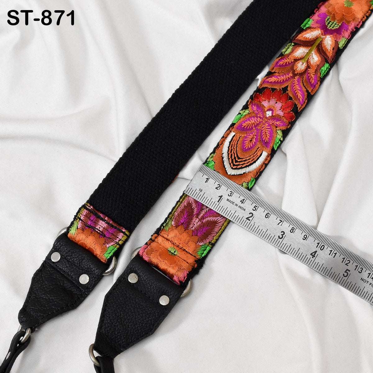 A colorful, floral-patterned strap with a black loop and a metal ruler placed on a white surface.
