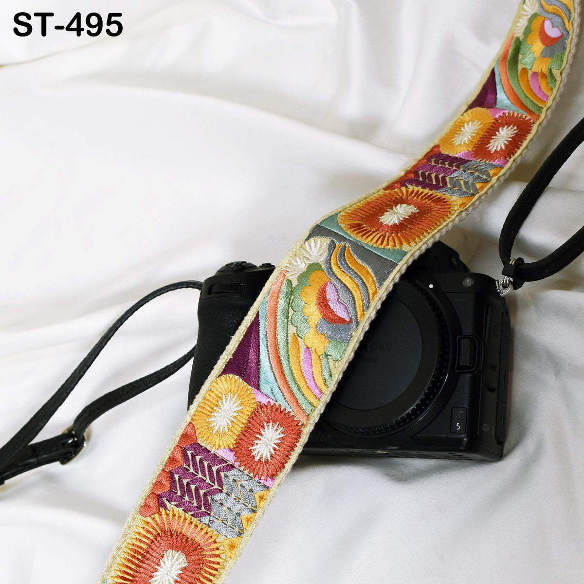 A colorful, patterned camera strap is draped over a black camera body, creating a visually striking contrast.