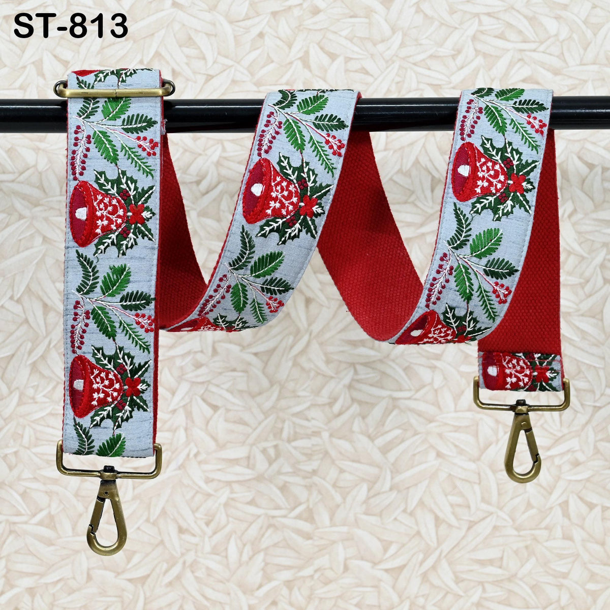A red and white patterned strap with a bell motif, hanging on a black rod.