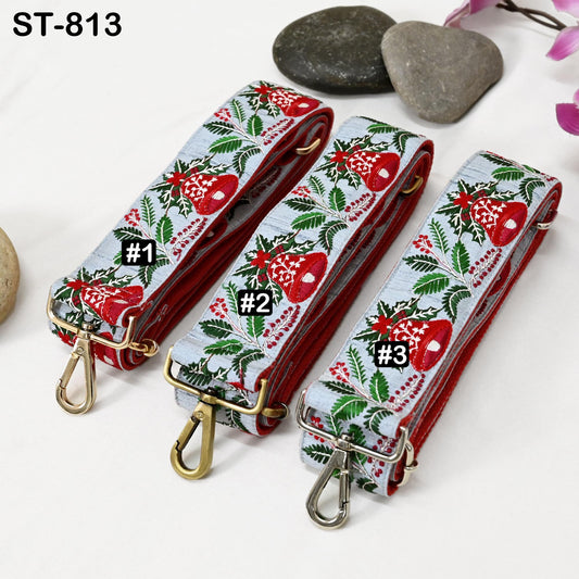 Three colorful straps with floral patterns are displayed on a white surface, accompanied by small rocks and a pink flower.