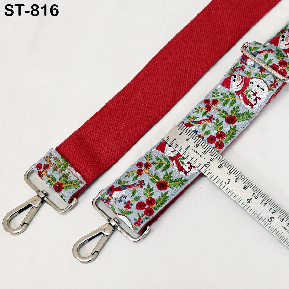 a red strap with a floral pattern and a ruler placed on top of it, indicating the strap's size.