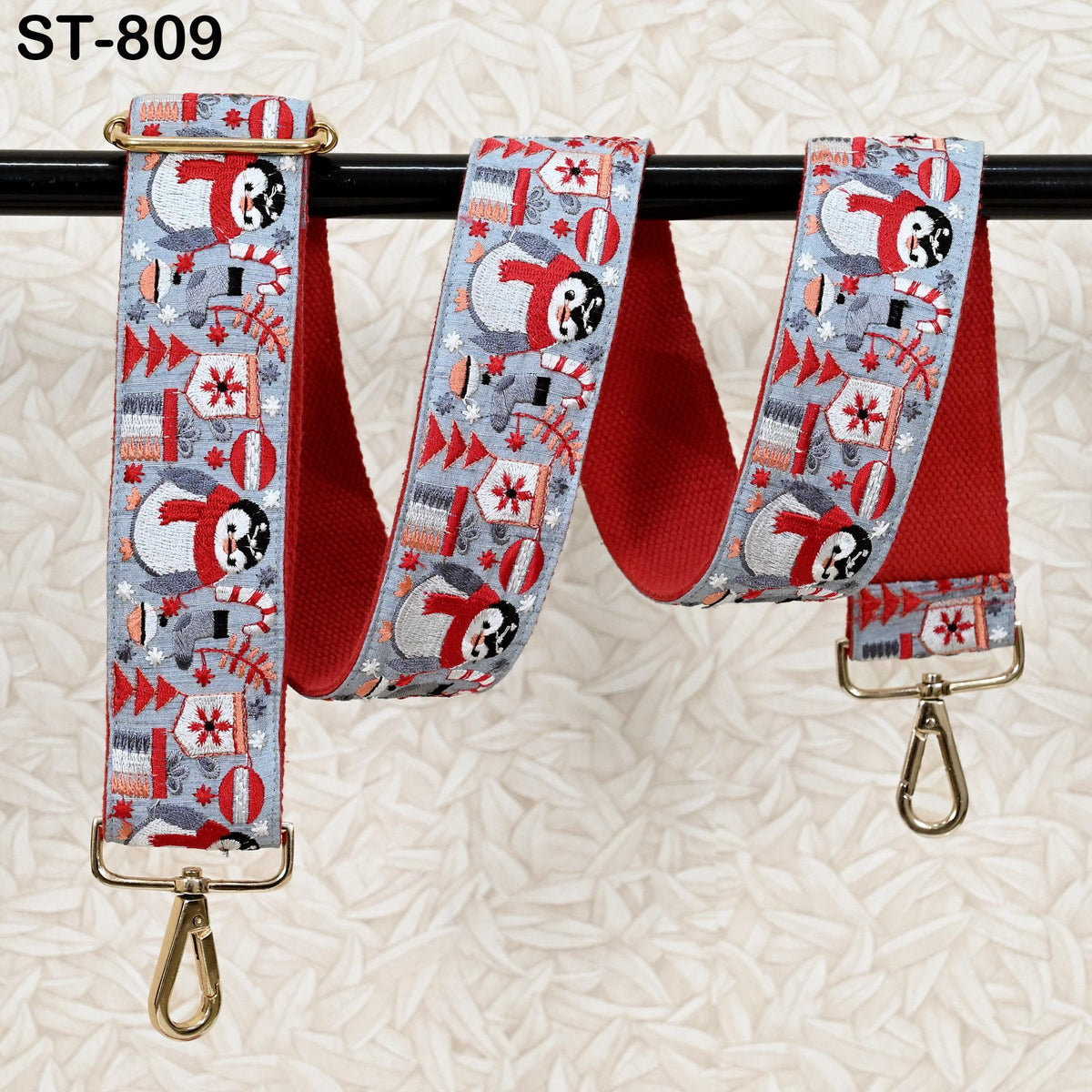 A pair of colorful, patterned straps with a Christmas-themed design, hanging on a black bar.