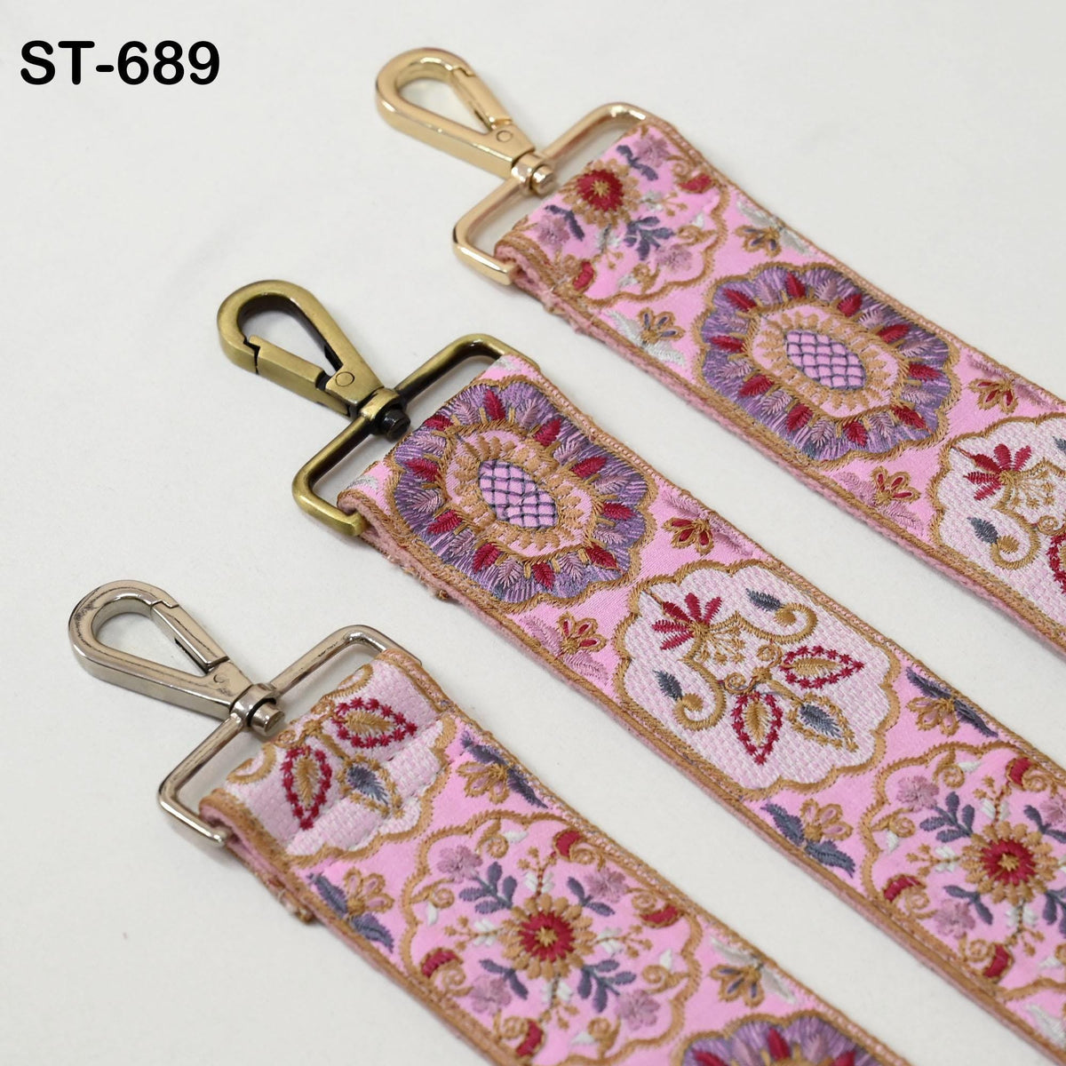 three straps with floral patterns in pink and gold colors. The straps have metal hooks and buckles, and they appear to be made of a soft, decorative fabric.