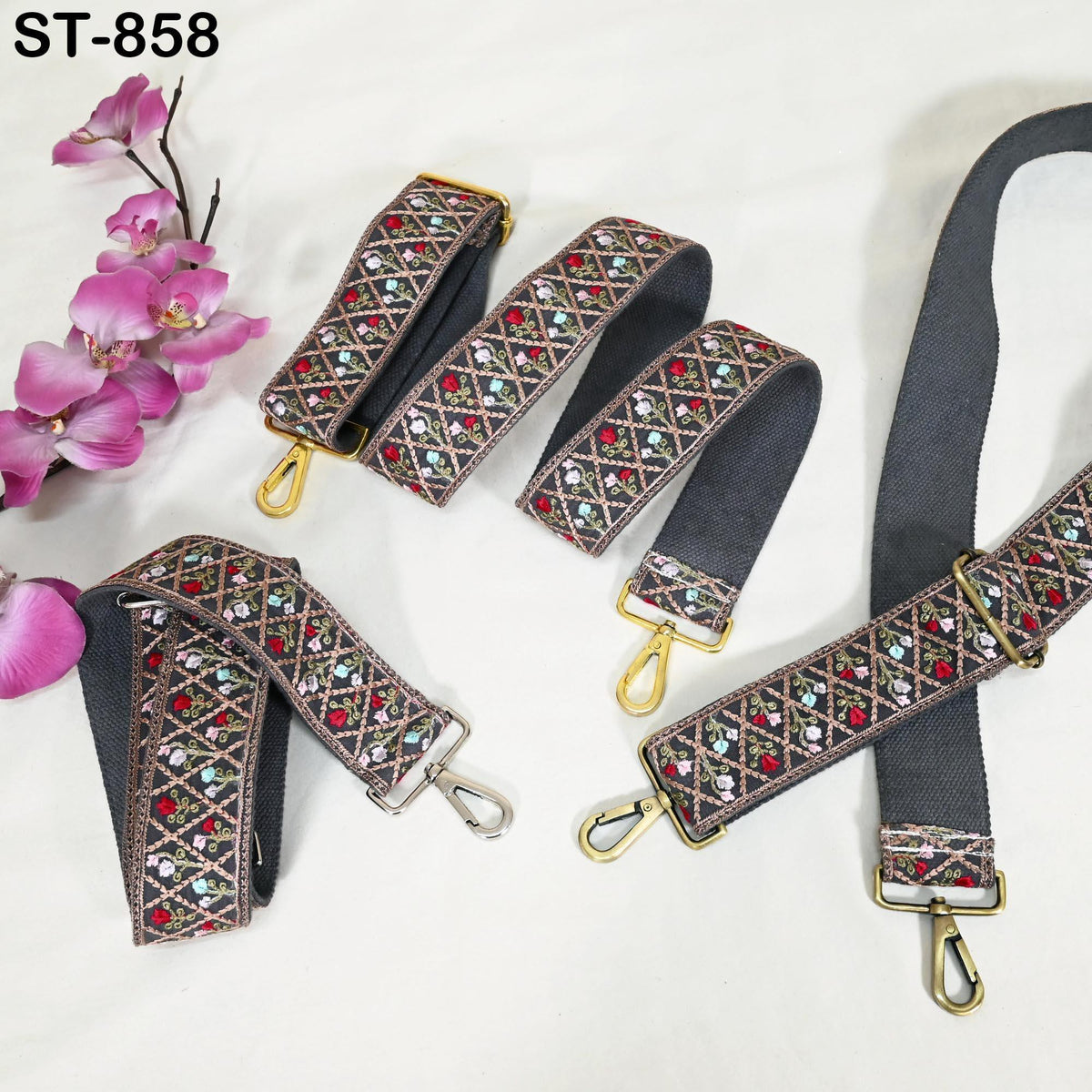 a collection of colorful, patterned straps with metal hardware, including buckles and clips, arranged on a white background. There are several straps in the foreground and background, showcasing a variety of designs and colors.
