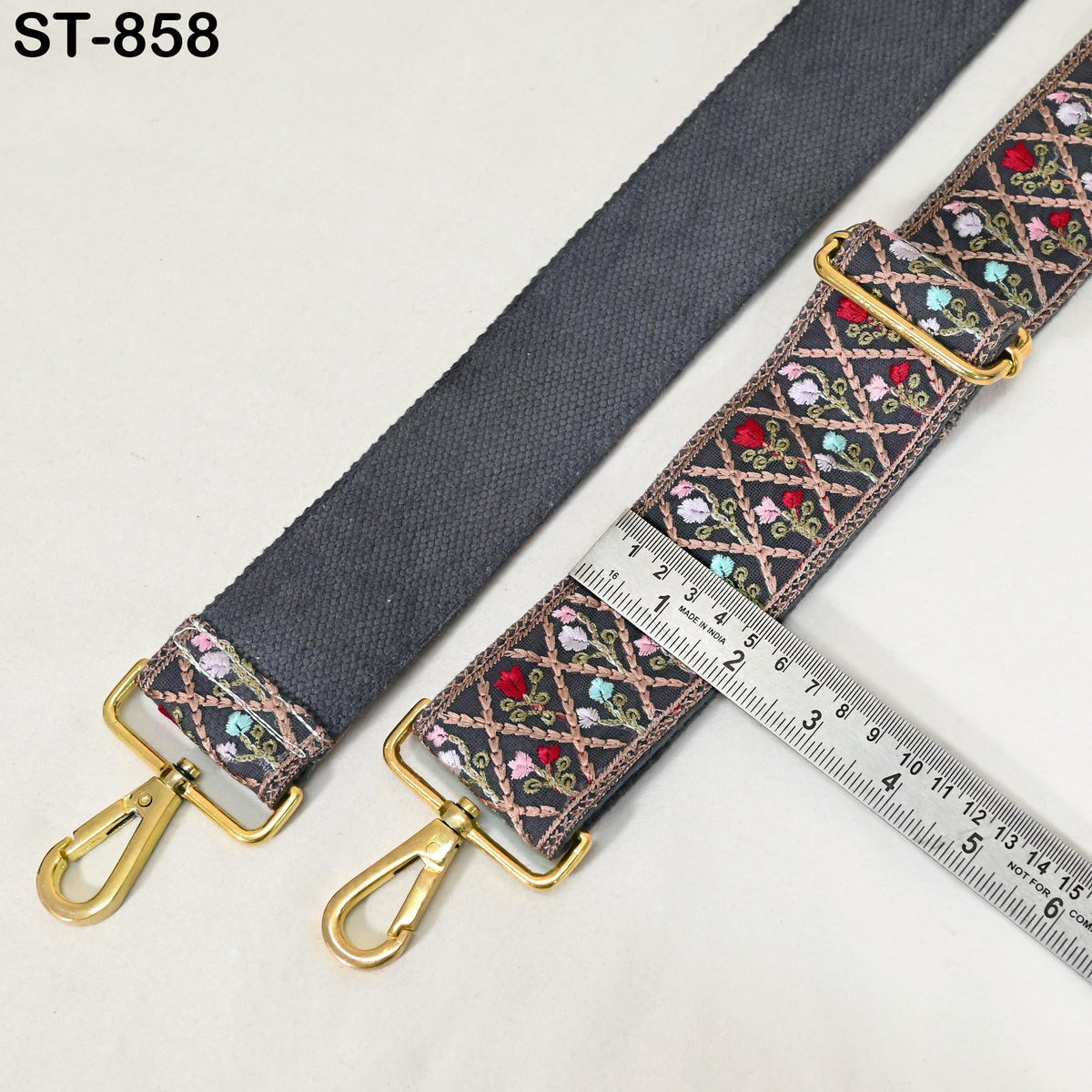 a black strap with a floral pattern and a ruler placed next to it, indicating the strap's size.