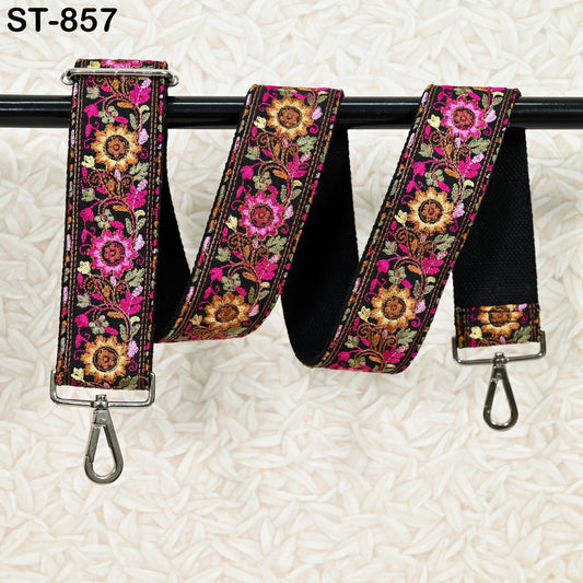 A colorful floral-patterned strap with a metal hook attached, hanging on a black bar.