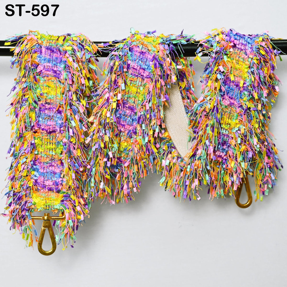 three colorful, fringed items hanging on a black rod.
