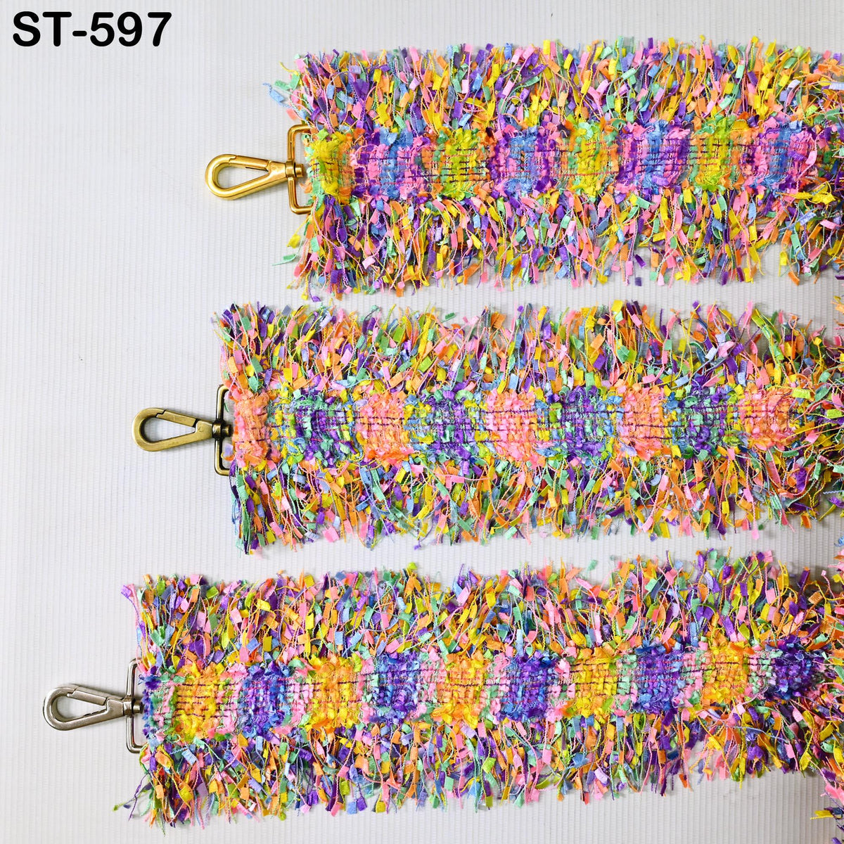 three colorful, textured straps with metallic buckles, arranged in a row.