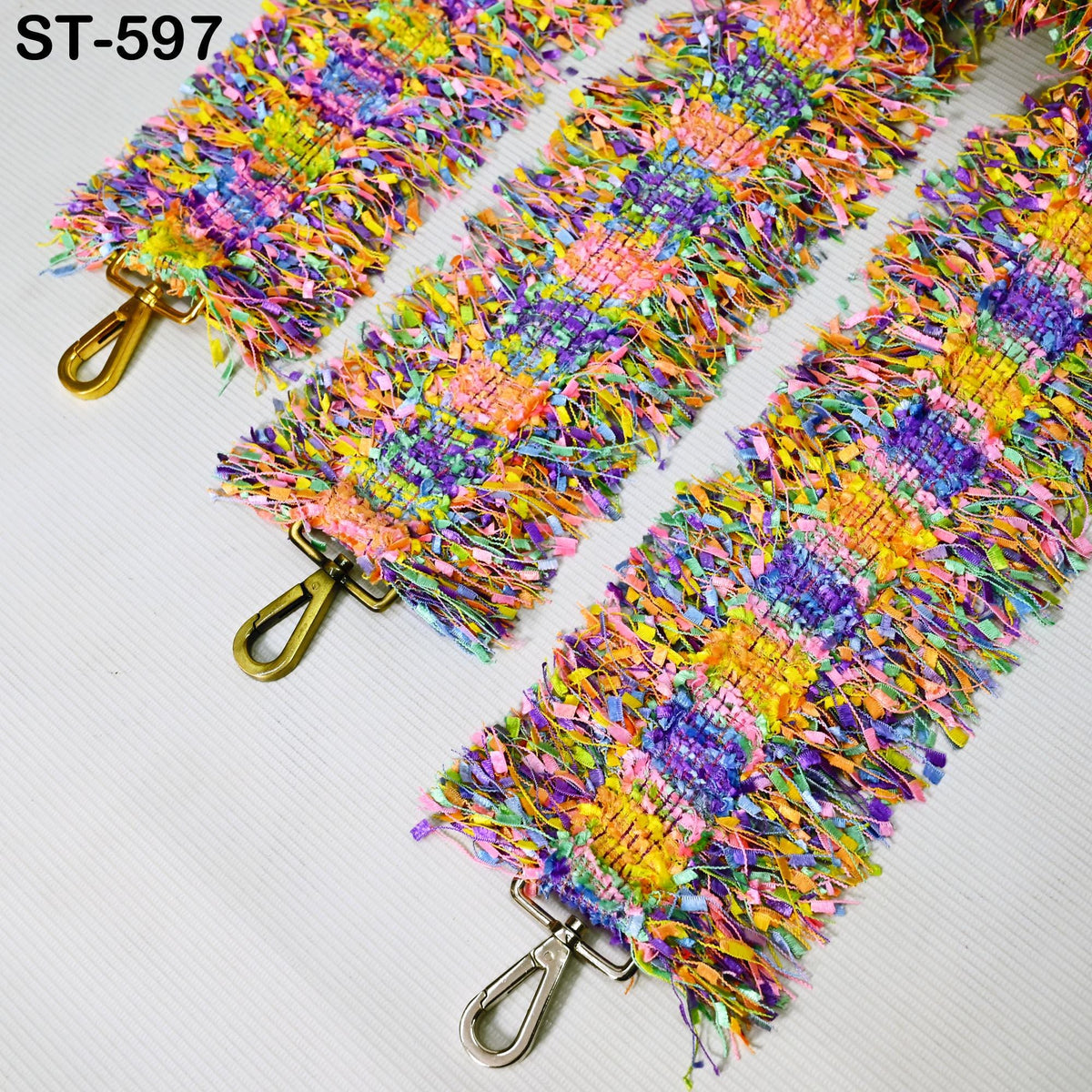 three colorful, textured straps with gold buckles, arranged side by side on a white surface.
