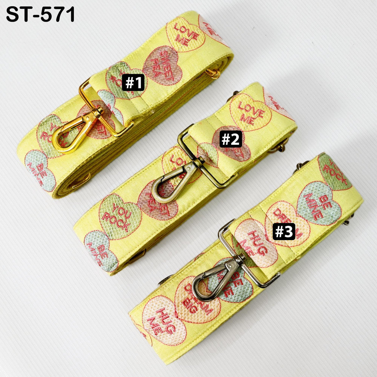 three yellow straps with heart-shaped charms on them, each with a different number printed on it.