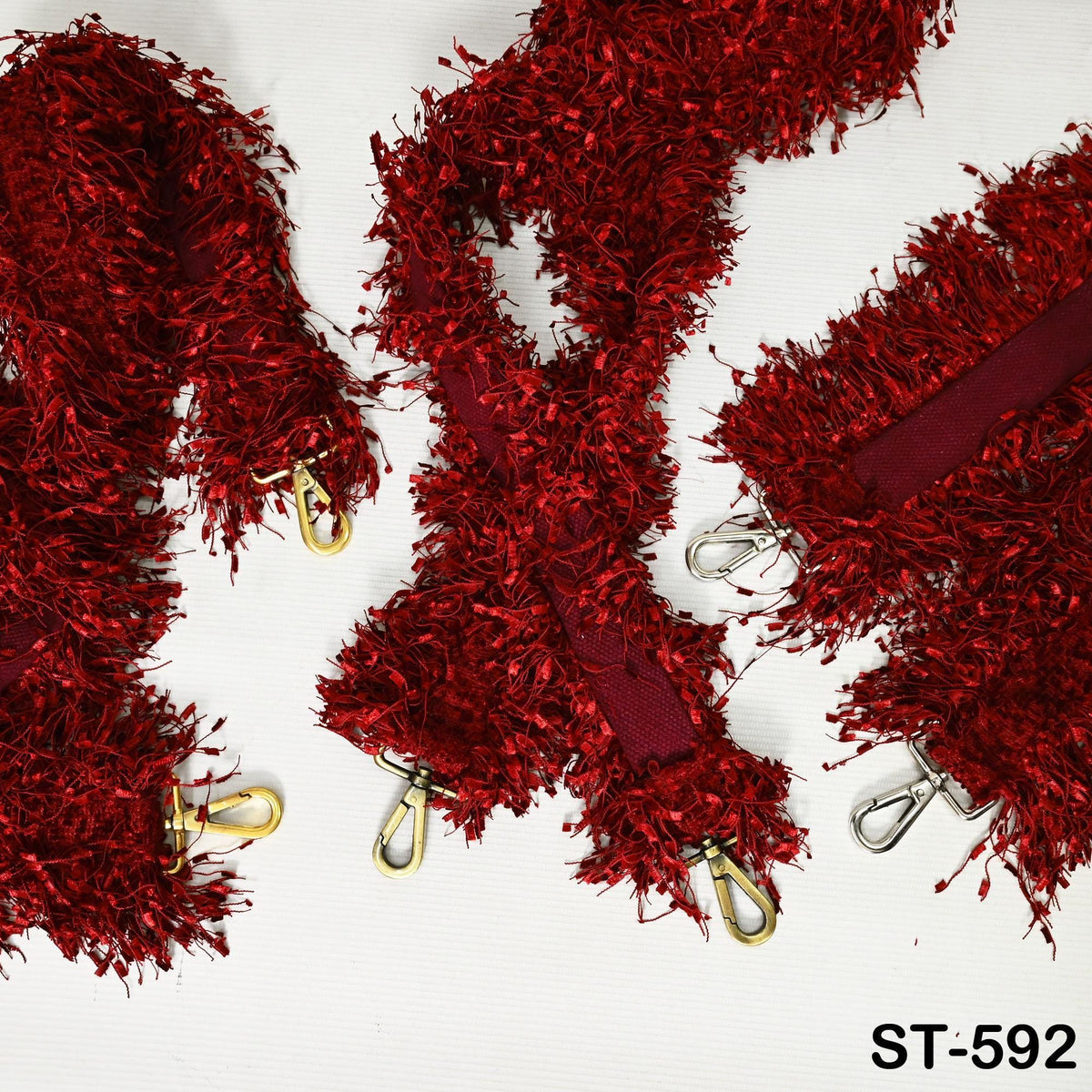 a collection of red, fuzzy straps or straps with gold buckles, arranged on a white background.
