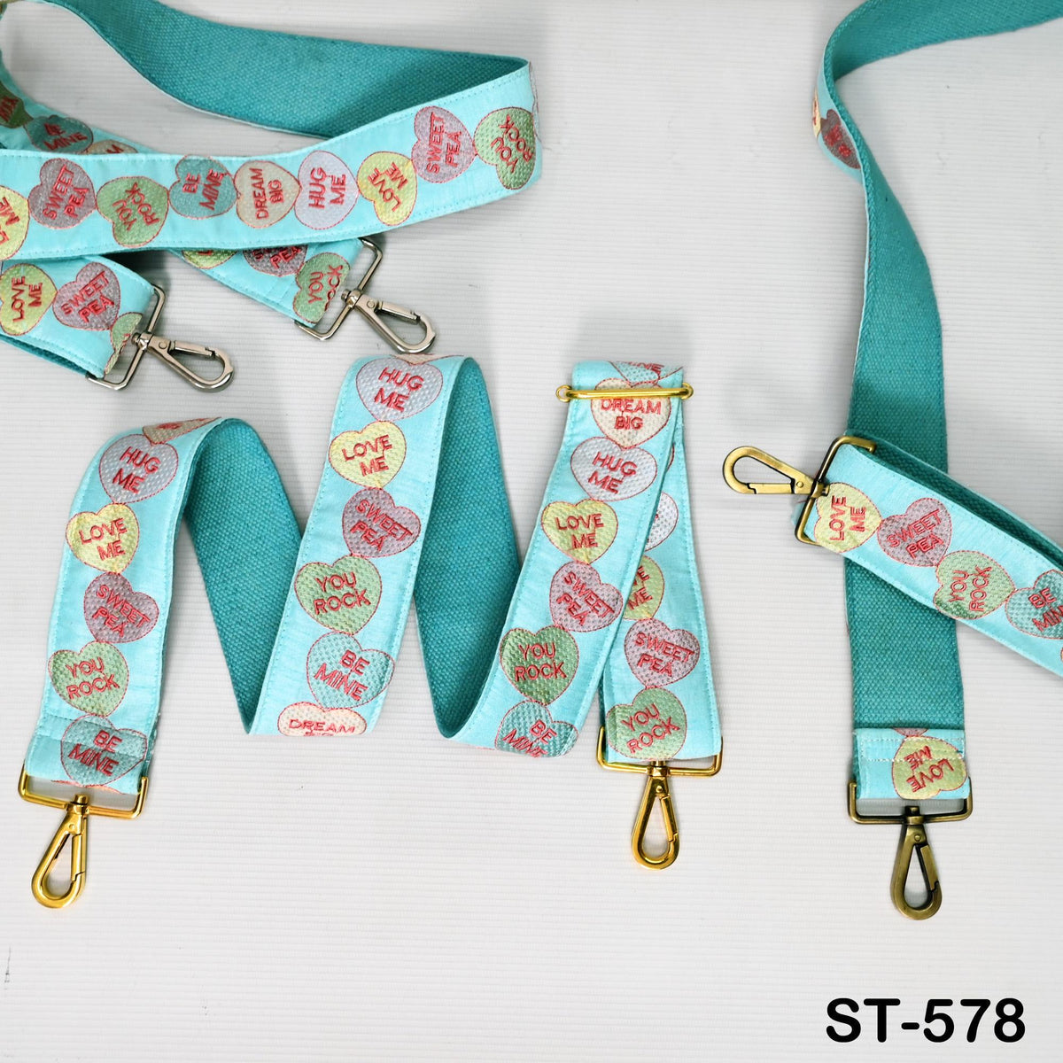 A collection of heart-shaped fabric straps in various colors, including turquoise, pink, and yellow, with the words "HUG ME" and "LOVE ME" printed on them.