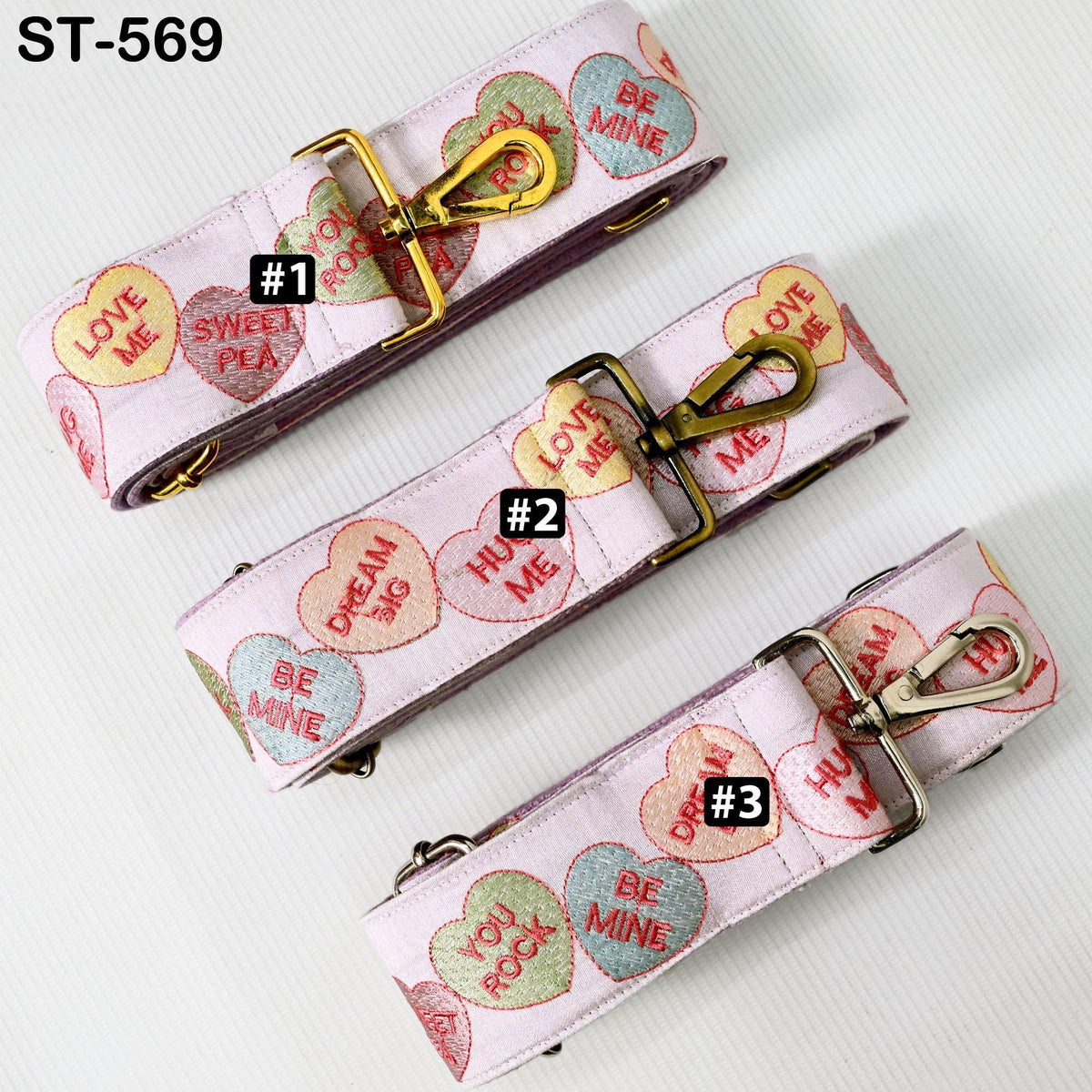 three pink straps with heart-shaped charms and the text "LOVE ME" printed on them.