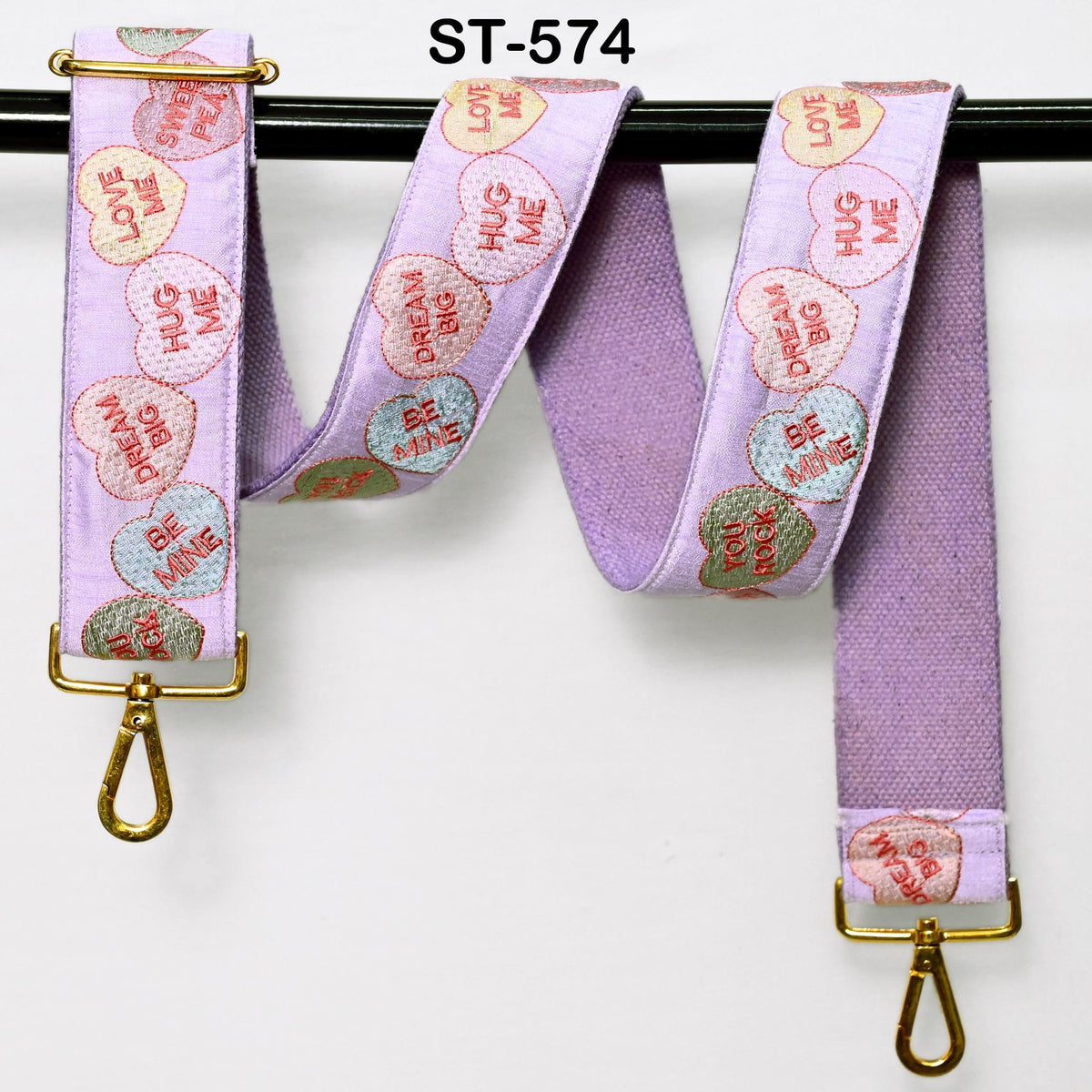 A purple strap with a heart-shaped embroidered pattern, featuring the words "LOVE ME" on it.