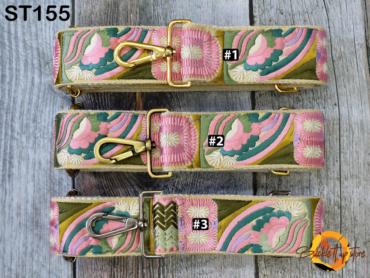 three colorful, patterned straps with gold hardware, arranged on a wooden surface.