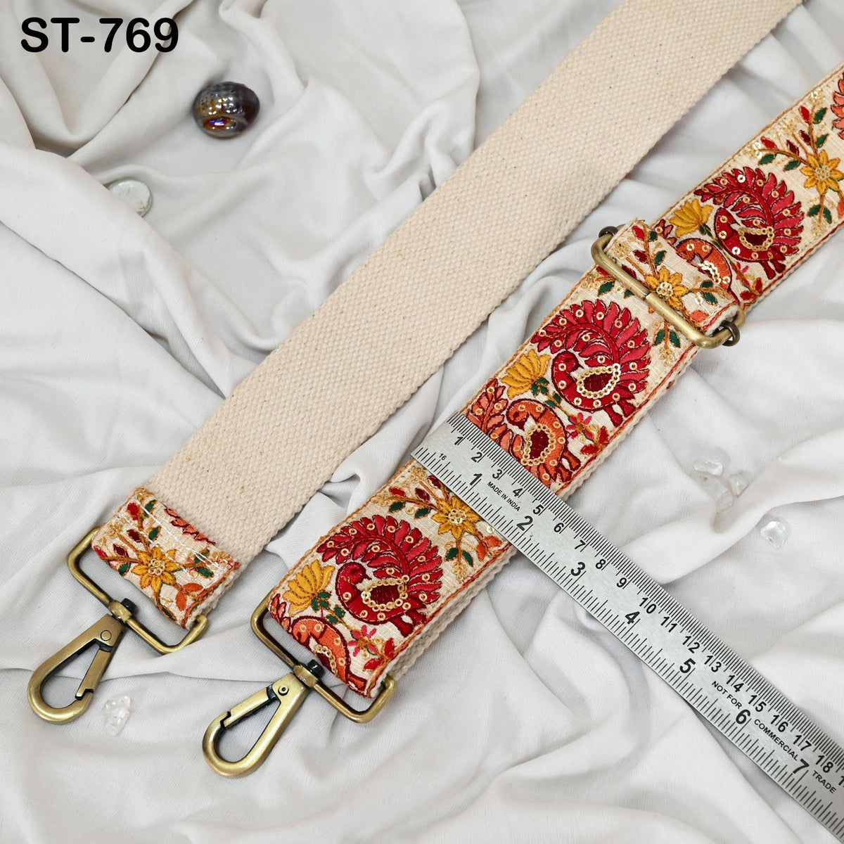 a beige strap with a floral pattern, placed on a white fabric surface. A ruler is visible next to the strap, indicating its size.