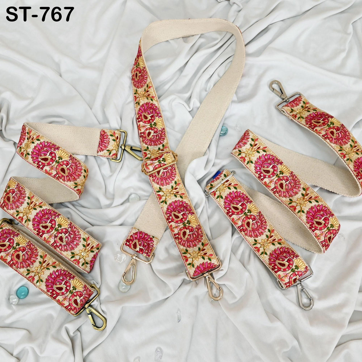 a collection of colorful, patterned straps or straps with metal buckles, arranged on a white fabric background.
