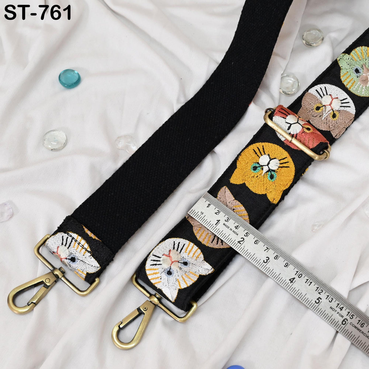 a black strap with a cat embroidered pattern and a ruler placed next to it, indicating the strap's length.