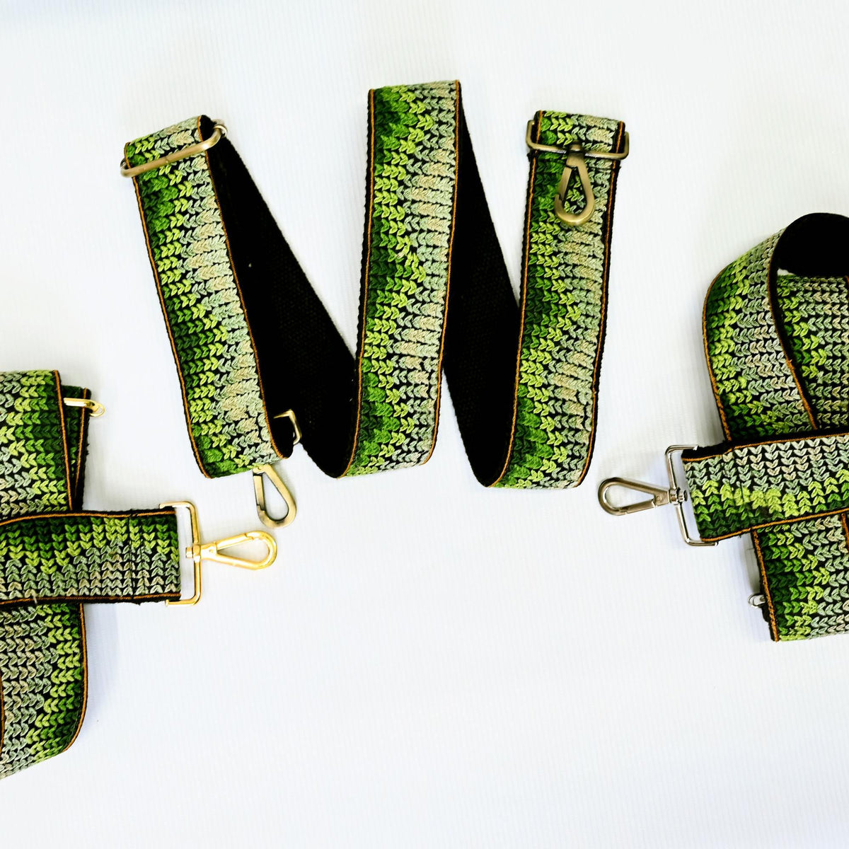 a collection of green and black straps with gold buckles, arranged in a circular pattern on a white background.