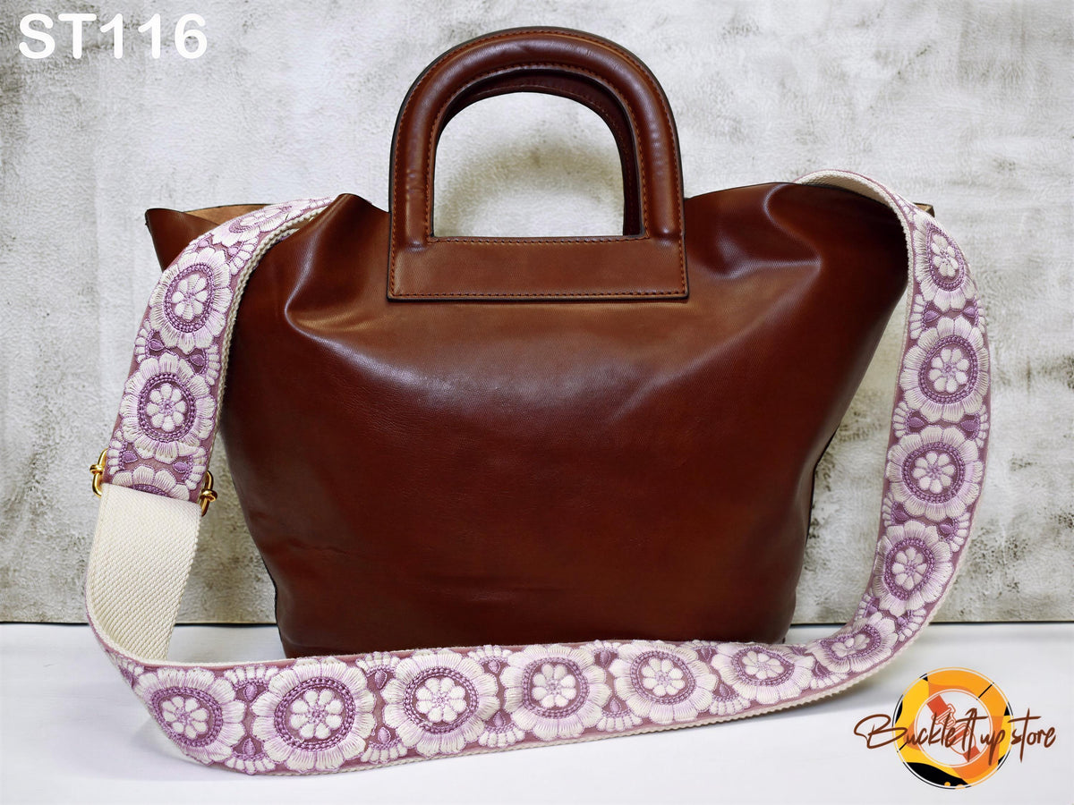 A brown leather handbag with a floral patterned strap is displayed against a white background.