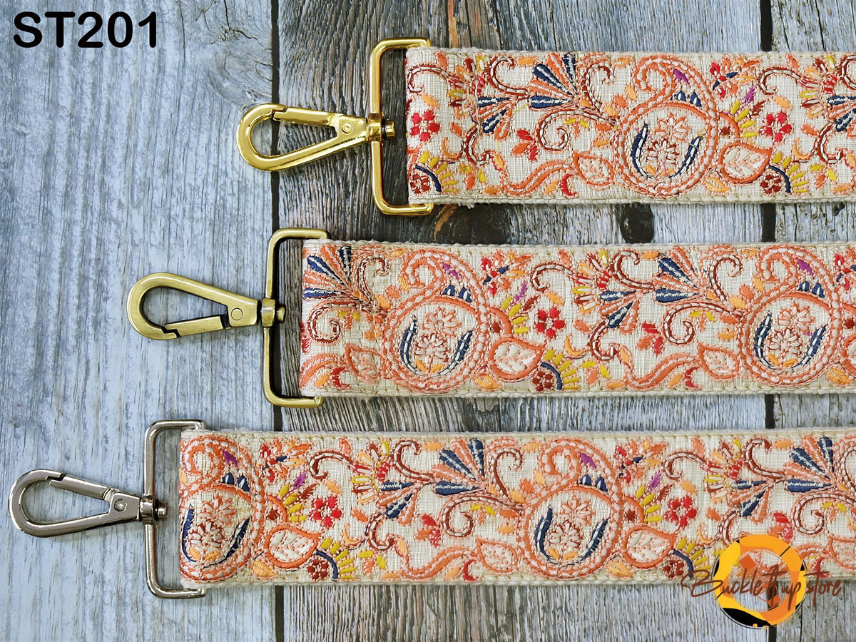 three colorful straps with floral patterns, each with a metal clasp and hook. The straps are arranged on a wooden surface, creating a visually appealing display.
