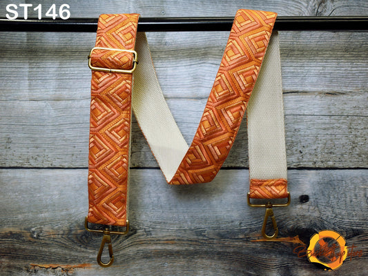 a pair of orange and white patterned suspenders hanging on a wooden surface.