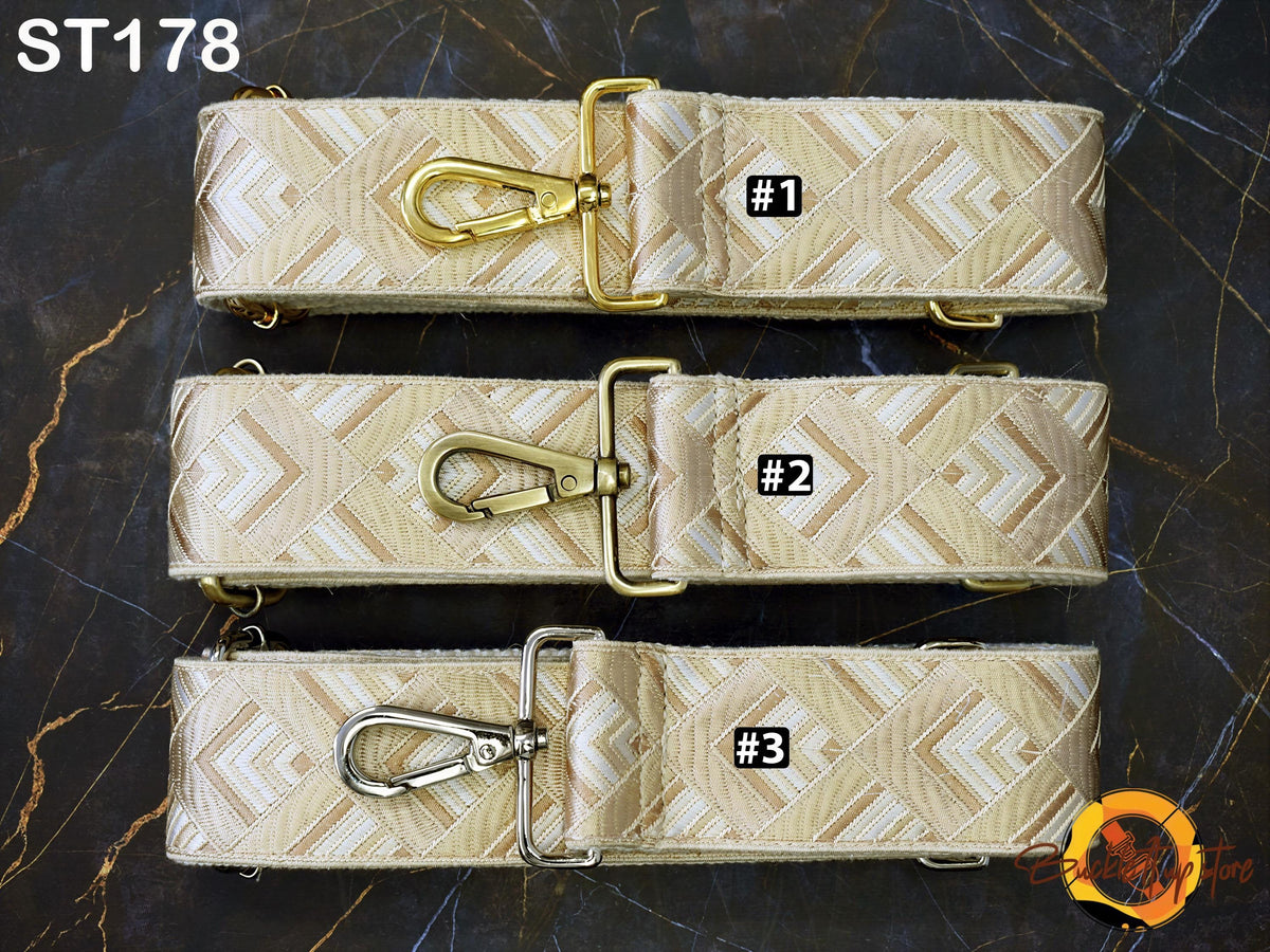 three beige and gold patterned straps with metal buckles, arranged in a row on a dark surface.