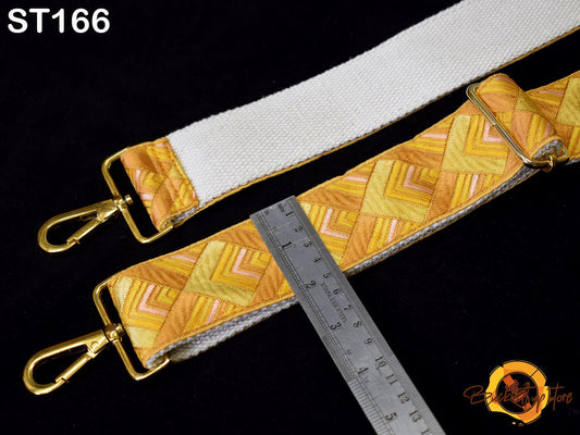 a strap with a geometric pattern in shades of yellow and orange, and a ruler placed next to it on a black background.
