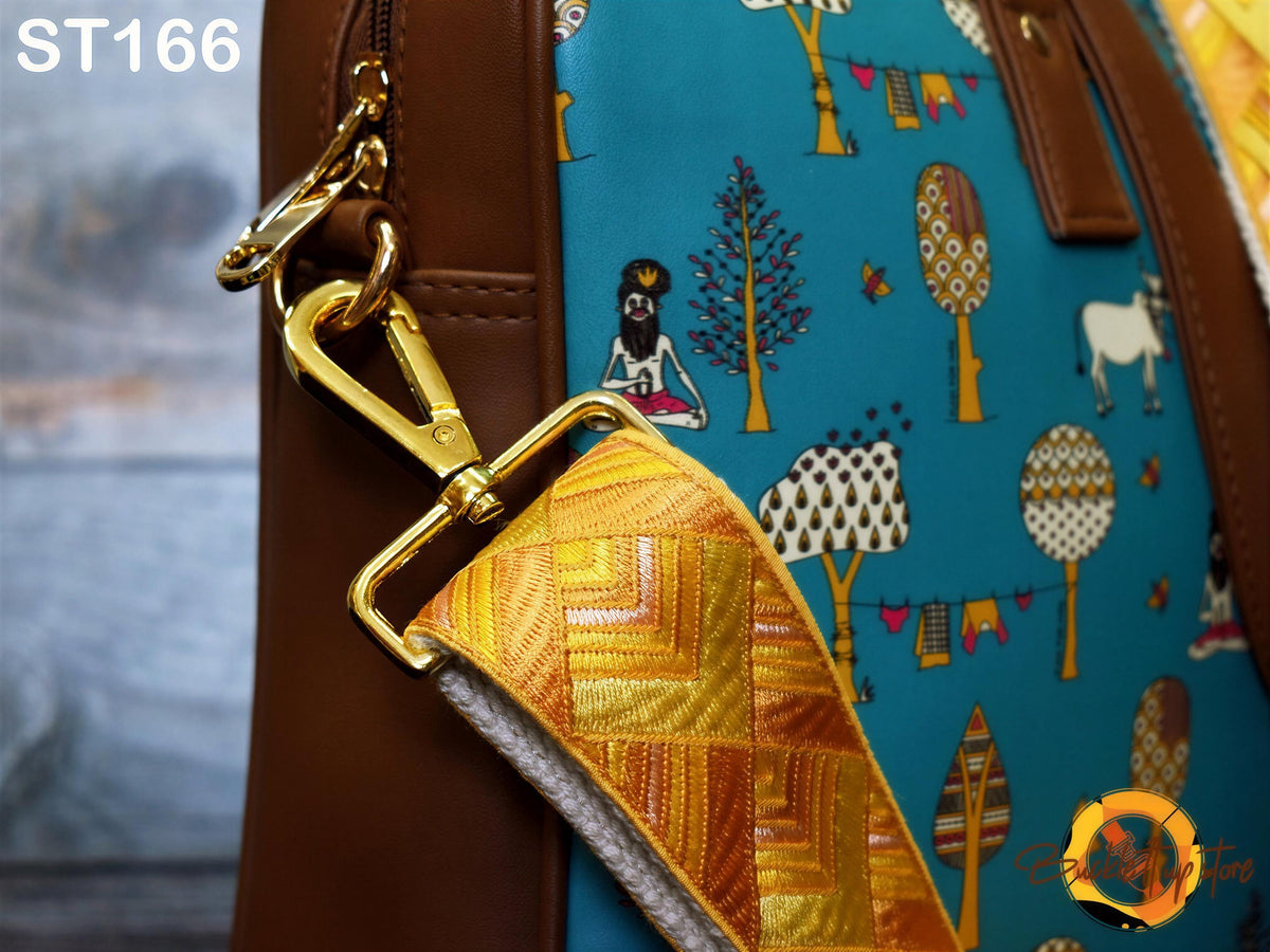 a close-up view of a handbag with a vibrant, colorful pattern on the fabric. The bag has a brown leather strap and a gold metal clasp, adding a touch of elegance to its design. The pattern on the fabric includes various illustrations of trees, flowers, and other natural elements, creating a lively and eye-catching appearance.